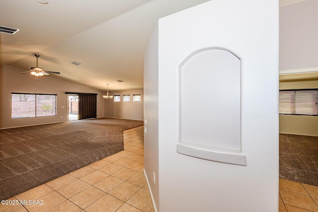 hallway featuring lofted ceiling, light tile patterned floors, visible vents, and light carpet