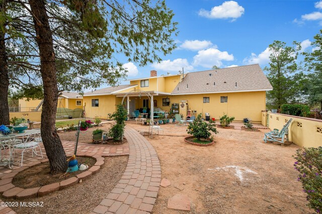 back of property with a patio area, stucco siding, a chimney, and fence