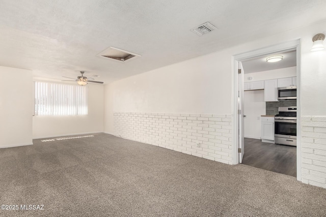 spare room featuring attic access, visible vents, dark carpet, and a textured ceiling