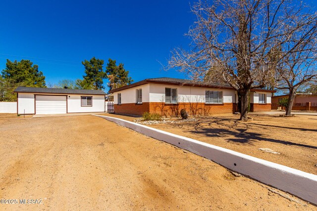single story home featuring stucco siding, driveway, an outdoor structure, a garage, and brick siding