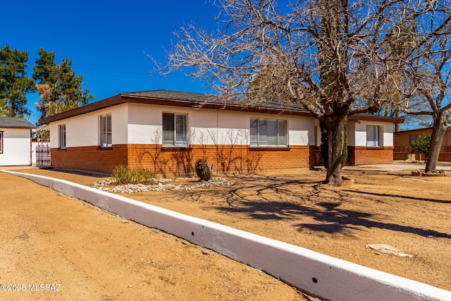 ranch-style home featuring stucco siding and brick siding