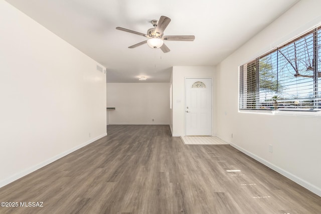 unfurnished living room with visible vents, ceiling fan, baseboards, and wood finished floors