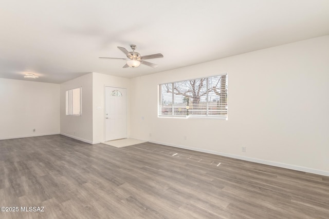 spare room featuring baseboards, wood finished floors, and a ceiling fan