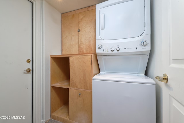 washroom with stacked washer and clothes dryer and cabinet space