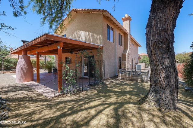 view of property exterior featuring a ceiling fan, a patio, stucco siding, and a chimney
