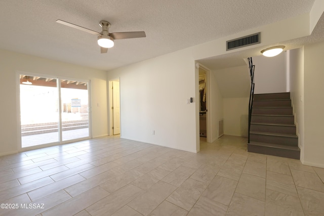 spare room featuring visible vents, a textured ceiling, a ceiling fan, and stairway