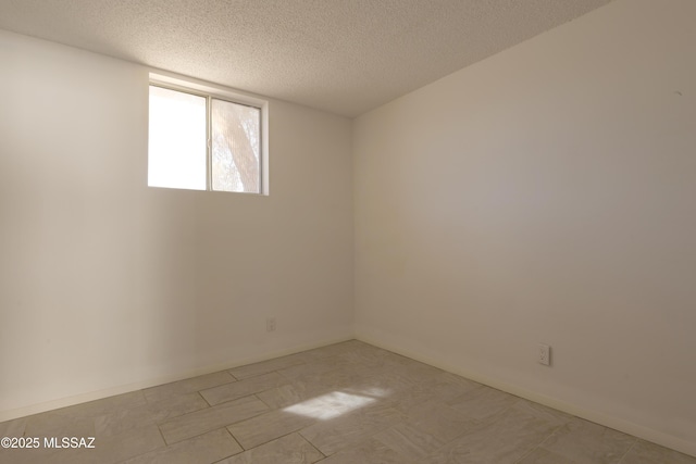 unfurnished room with baseboards and a textured ceiling