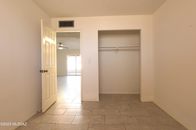 unfurnished bedroom featuring visible vents, a textured ceiling, and baseboards