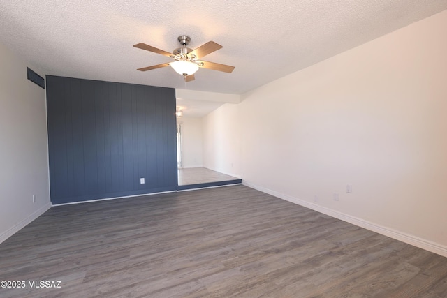 empty room with wood finished floors, a ceiling fan, and a textured ceiling