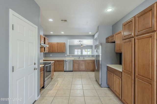 20868 E Treasure Rd, Red Rock, AZ 85145 - kitchen featuring brown cabinetry, visible vents, stainless steel appliances, light countertops, and under cabinet range hood