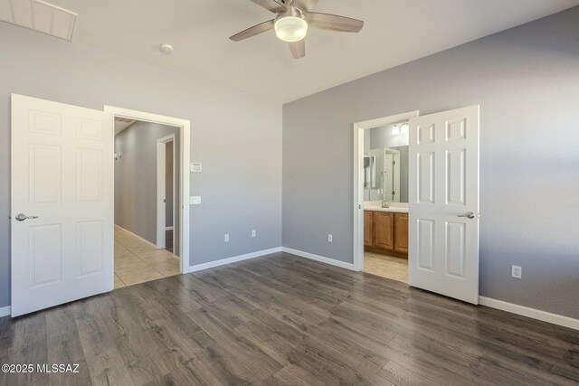 20868 E Treasure Rd, Red Rock, AZ 85145 - unfurnished bedroom with visible vents, connected bathroom, baseboards, and wood finished floors