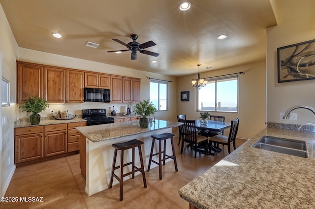 9505 S Deer Ridge Trl, Hereford, AZ 85615 - kitchen with a sink, a breakfast bar, visible vents, black appliances, and brown cabinetry