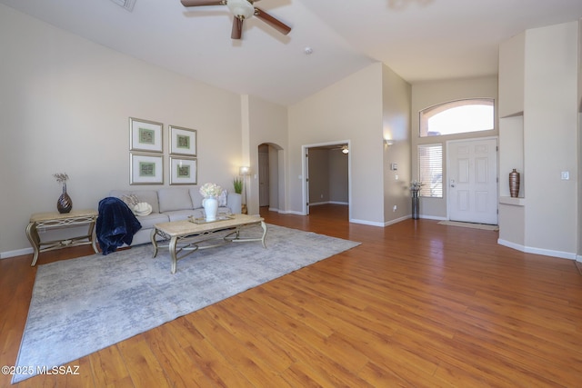 8418 N Sayante Way, Tucson, AZ 85743 - unfurnished living room with light wood finished floors, high vaulted ceiling, arched walkways, and a ceiling fan