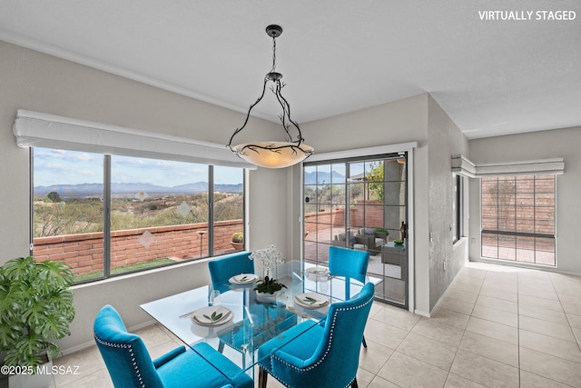 dining space with light tile patterned flooring, a mountain view, and baseboards