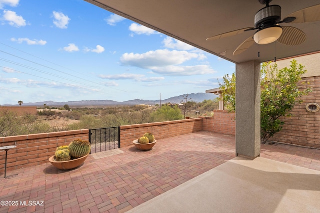 view of patio with a mountain view, fence, and a ceiling fan