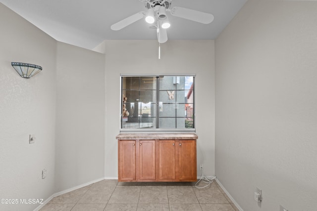 spare room featuring baseboards, a ceiling fan, and light tile patterned flooring
