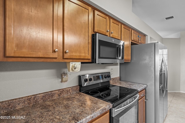 kitchen featuring visible vents, appliances with stainless steel finishes, light tile patterned flooring, dark countertops, and brown cabinets