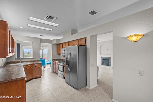 kitchen with appliances with stainless steel finishes, a sink, visible vents, and dark countertops