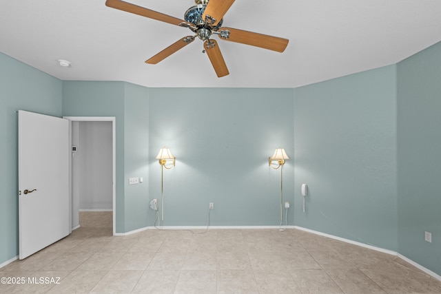 empty room with ceiling fan, baseboards, and tile patterned flooring