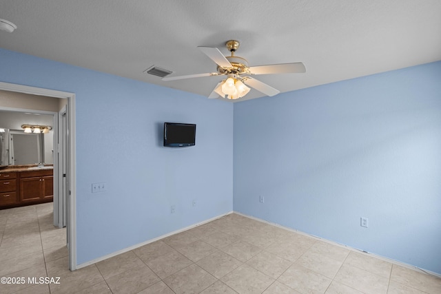unfurnished bedroom with baseboards, light tile patterned floors, visible vents, ceiling fan, and a sink