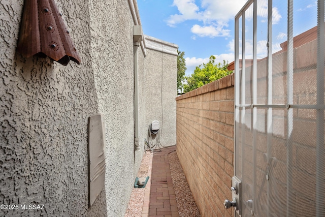 view of side of home featuring fence and stucco siding