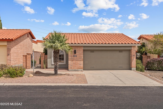mediterranean / spanish-style home with a gate, a tile roof, brick siding, a garage, and concrete driveway