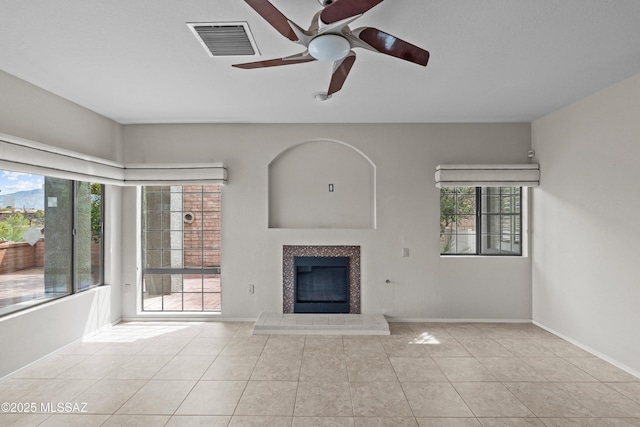 unfurnished living room with a tiled fireplace, visible vents, ceiling fan, and tile patterned flooring