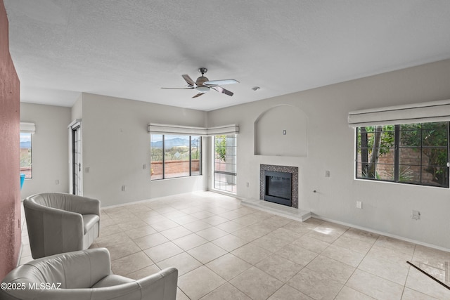 living area featuring a healthy amount of sunlight, a high end fireplace, light tile patterned flooring, and ceiling fan
