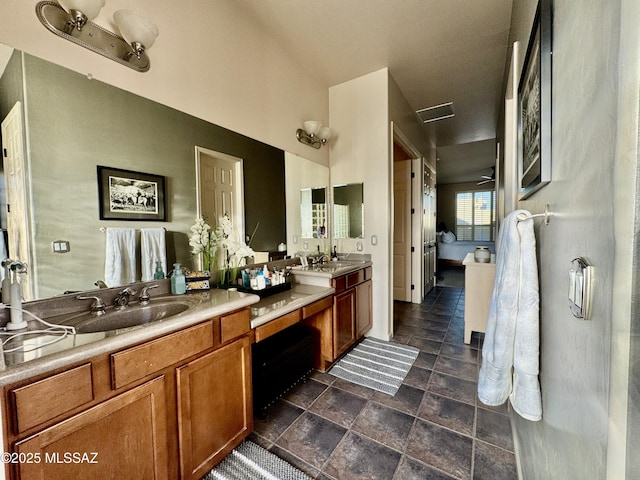 full bath featuring ensuite bathroom, double vanity, a sink, and stone finish floor
