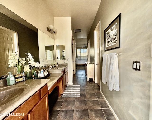 full bathroom with baseboards, visible vents, double vanity, and a sink