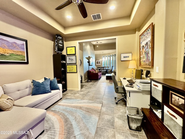 office space featuring a raised ceiling, baseboards, ceiling fan, and visible vents
