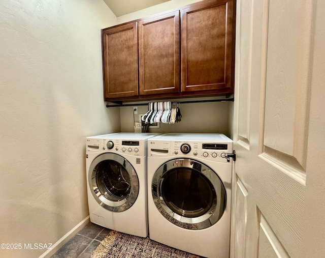 laundry area featuring baseboards, cabinet space, dark tile patterned flooring, and washer and clothes dryer