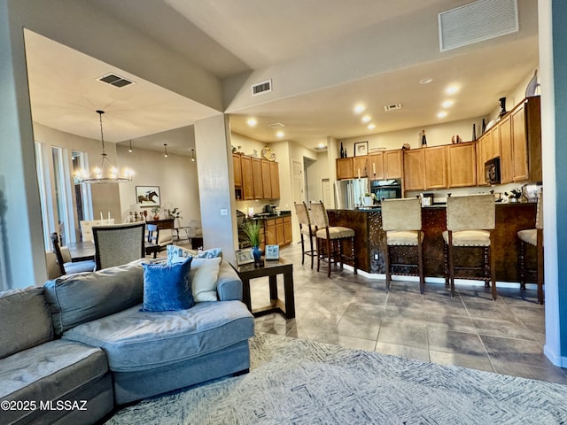 tiled living room featuring visible vents and a notable chandelier