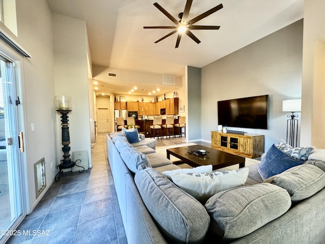 living room with baseboards, visible vents, and a ceiling fan