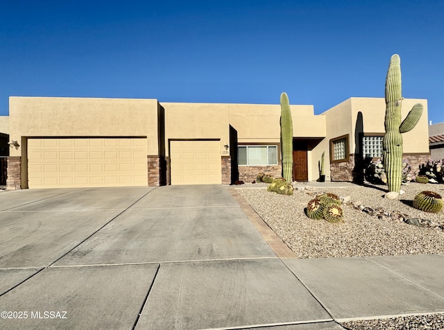 southwest-style home with stone siding, driveway, an attached garage, and stucco siding