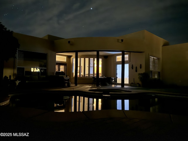 pool at twilight with a pool with connected hot tub and a patio area