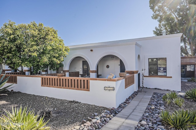 view of front facade featuring stucco siding and fence