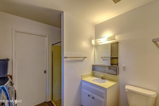 bathroom with toilet, vanity, tiled shower, and stacked washing maching and dryer