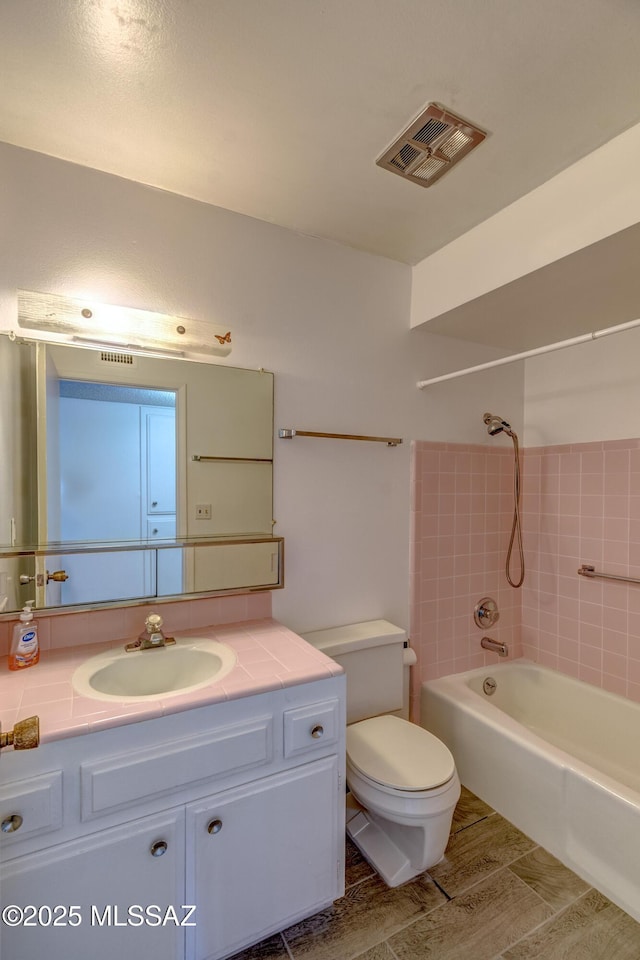 bathroom with toilet, vanity, shower / bathtub combination, wood tiled floor, and visible vents