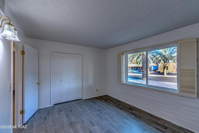 unfurnished bedroom with a textured ceiling, a closet, and wood tiled floor
