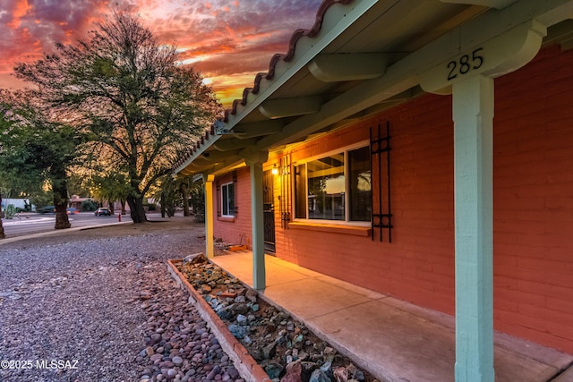 property exterior at dusk featuring brick siding