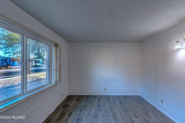 unfurnished room featuring dark wood-type flooring and a textured ceiling