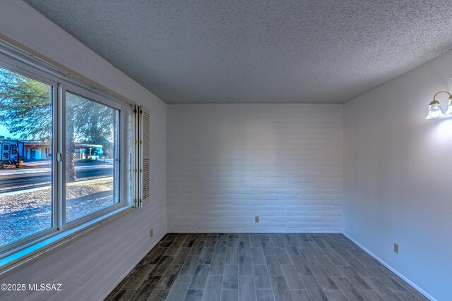 285 E Los Rincones, Green Valley, AZ 85614 - empty room with brick wall, dark wood-type flooring, a textured ceiling, and baseboards