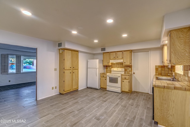 285 E Los Rincones, Green Valley, AZ 85614 - kitchen featuring white appliances, under cabinet range hood, a sink, tile countertops, and decorative backsplash