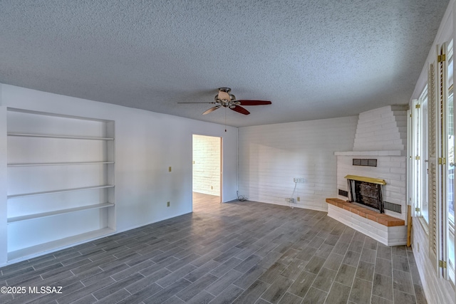 unfurnished living room featuring wood tiled floor, a textured ceiling, ceiling fan, and a brick fireplace