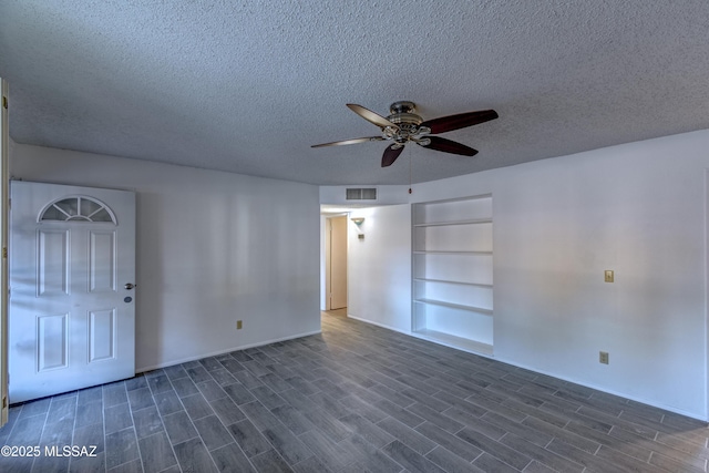 empty room featuring a textured ceiling, dark wood-style flooring, ceiling fan, and visible vents