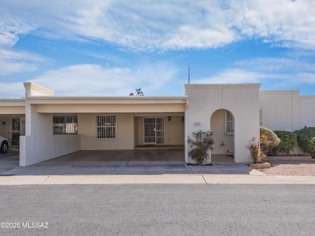 view of front facade with an attached carport and stucco siding