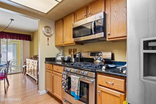 kitchen featuring appliances with stainless steel finishes, light wood-type flooring, and baseboards