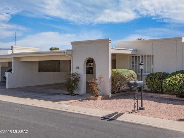 view of front of house featuring a carport, driveway, and stucco siding