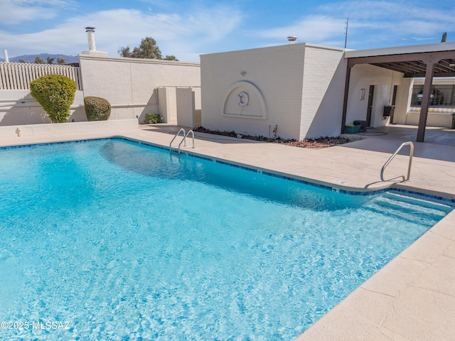 pool with a patio area and fence